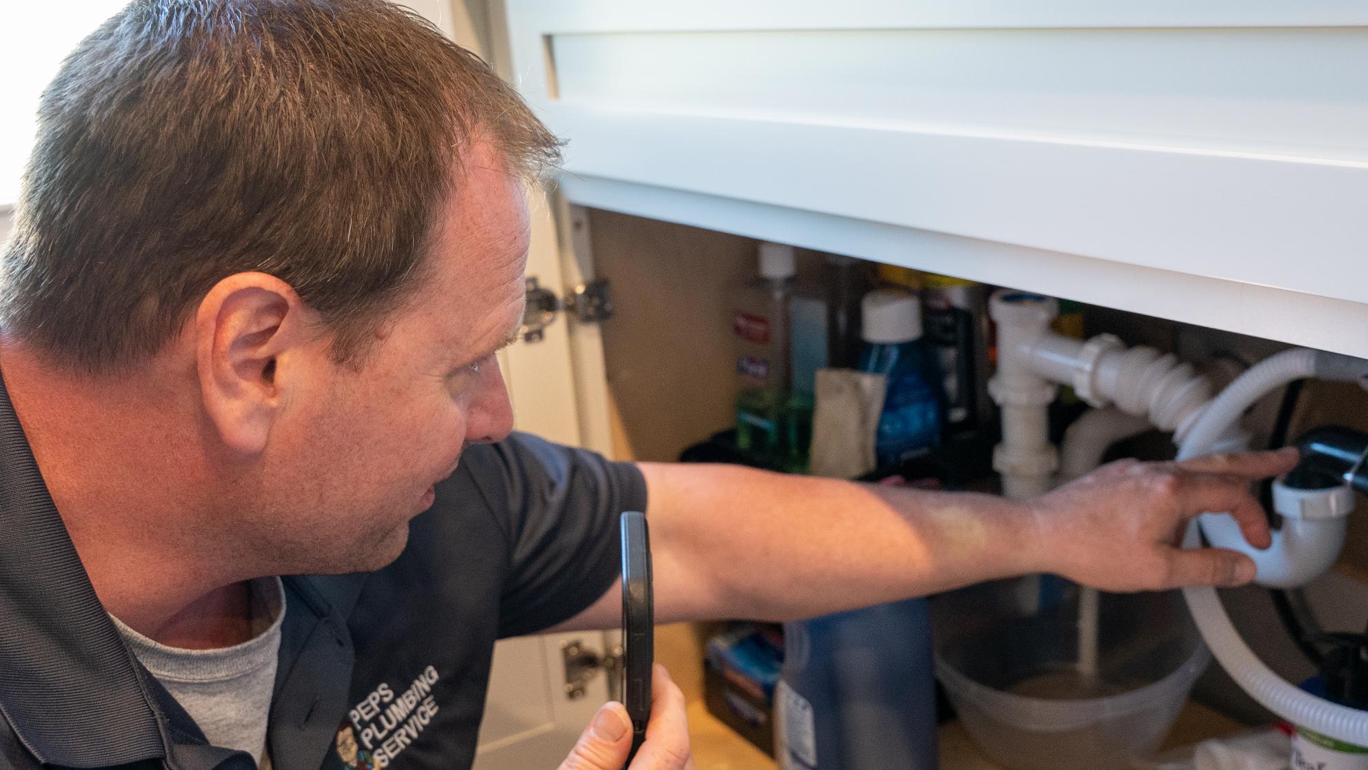 Peps plumber checking a leak under a sink